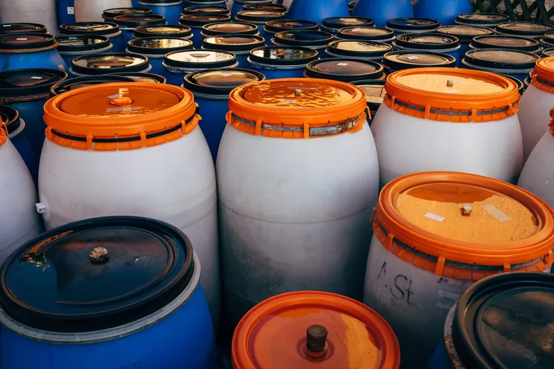 Rows of sealed blue and white barrels with orange lids